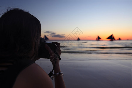 女人拍游艇的照片女人日落时拍摄游艇热带海洋航行的照片图片
