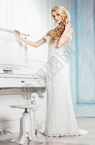 穿着白色连衣裙的新娘钢琴附近摆姿势图片