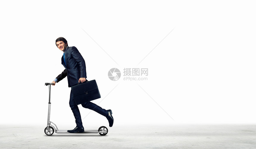 商人骑滑板车穿着黑色西装骑滑板车的轻商人的形象图片