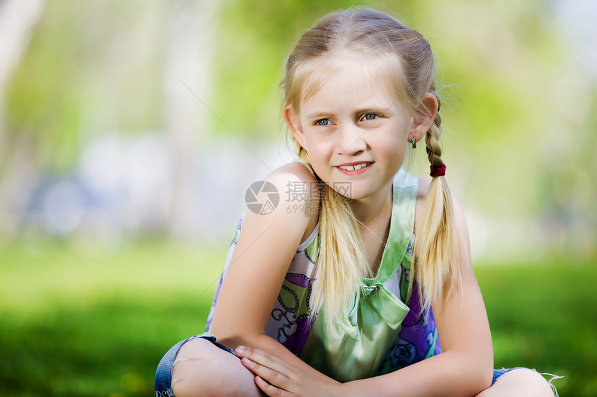 公园里的小女孩公园里坐草地上的小可爱女孩的形象图片