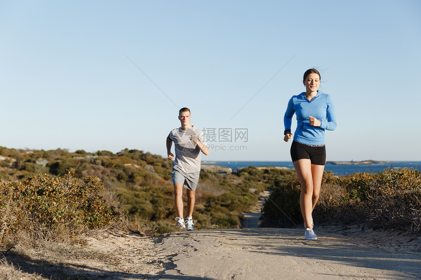 运动跑步者海滩上慢跑,她的搭档锻炼适合女健身模式慢跑沿海洋与她的伴侣图片