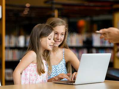 电子书籍图书馆里着笔记本电脑的小女孩图书馆的技术乐趣背景