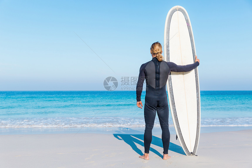 个轻的冲浪者海滩上冲浪等待个完美的波图片