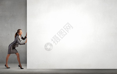 女人推横幅吸引力的女商人推着白色的空白墙文字的位置图片