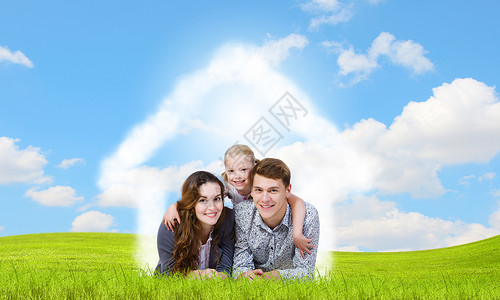 轻的家庭幸福的三口之家躺绿色的草地上图片