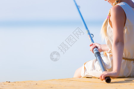 钓鱼女孩穿着连衣裙帽子的女孩带着钓鱼竿码头钓鱼背景