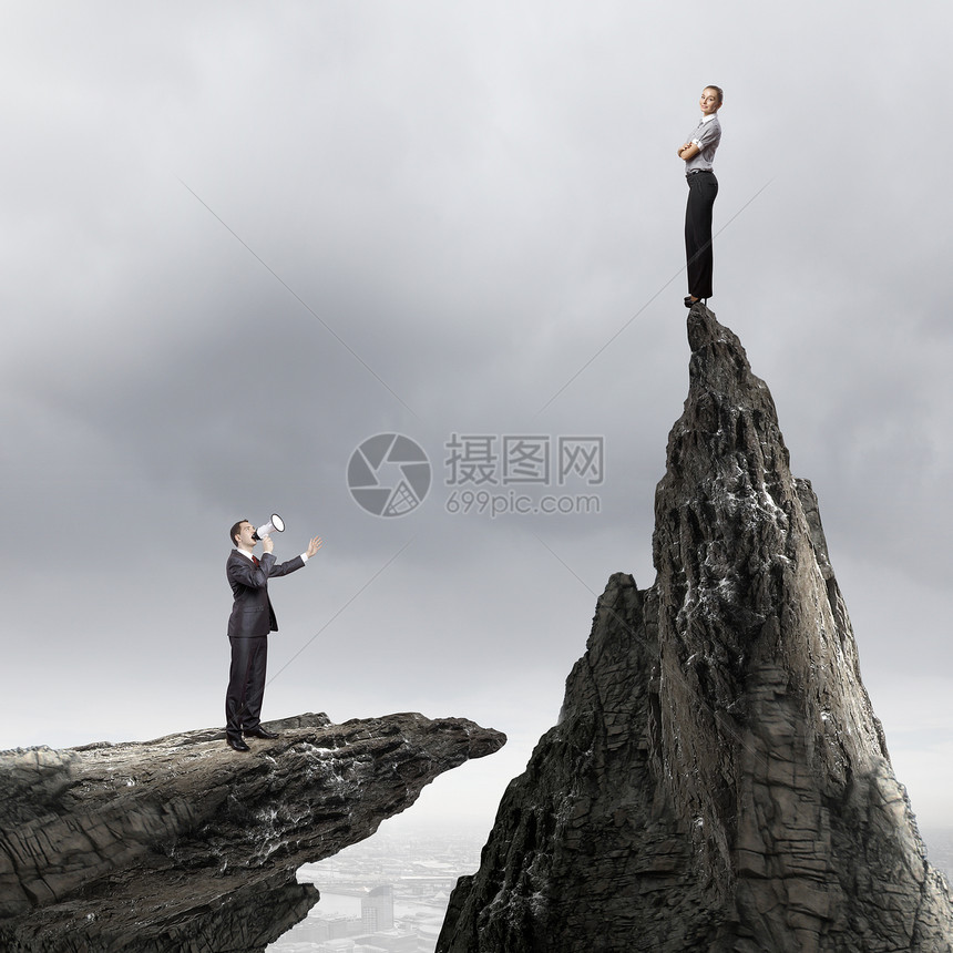竞争力的生意女商人站岩石上,商人用扩音器尖叫图片