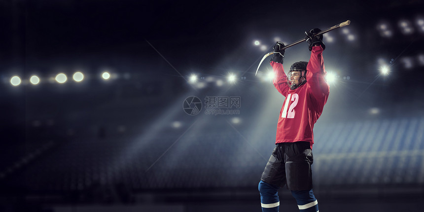 冰球运动员冰上穿着红色制服的曲棍球运动员聚光灯下的冰场上图片