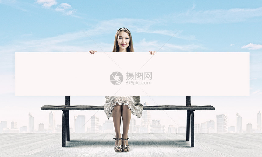 带横幅的女孩轻的亚洲女人坐长凳上,着空白的横幅图片