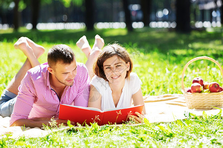 轻的浪漫夫妇躺公园里看书公园休息图片