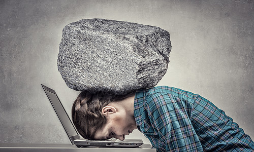 工作的压力下女程序员用沉重的石头压笔记本电脑上图片