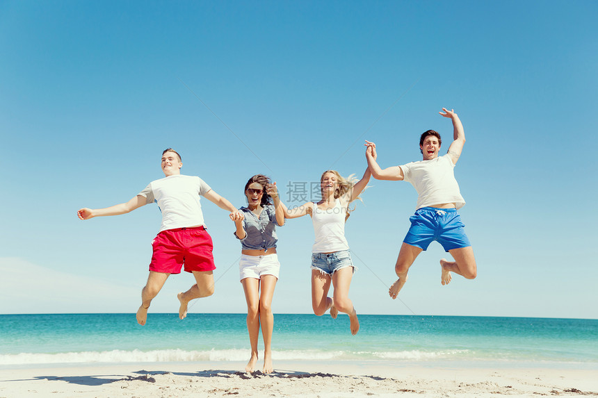 海滩上轻人的陪伴轻朋友海滩上玩跳跃的乐趣图片