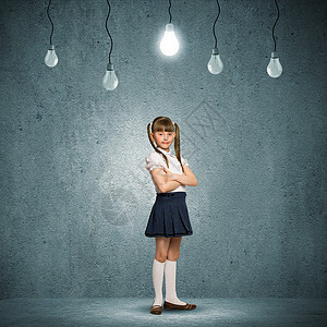 神童可爱的学校女孩靠灰色的墙上,挂着灯泡图片
