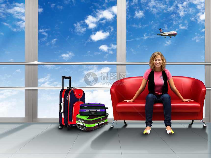 轻的女人坐机场的红色沙发上图片