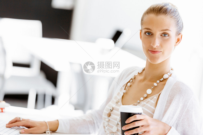 坐办公桌前的吸引力的上族魅力的女人坐办公室的桌子上喝咖啡图片
