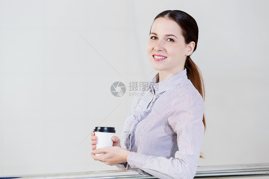 咖啡休息时间随意的白种女人站阳台上,手里着咖啡图片