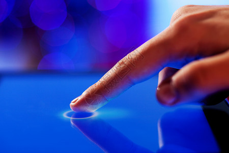 手指触摸屏幕手指触摸蓝色屏幕的特写图像图片