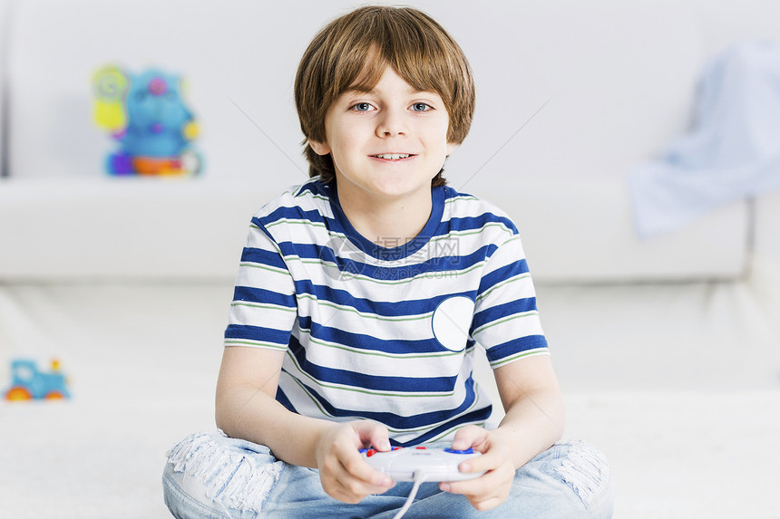 男孩坐地板上,用操纵杆敲打喜欢电子游戏图片