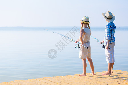 鱼竿的男孩女孩男孩女孩带着钓鱼竿码头钓鱼背景图片