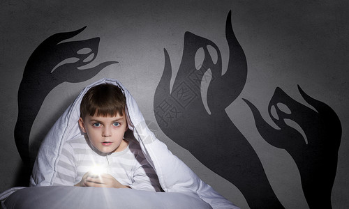 孩子的噩梦带着手电筒躺毯子下的小吓坏了的男孩图片