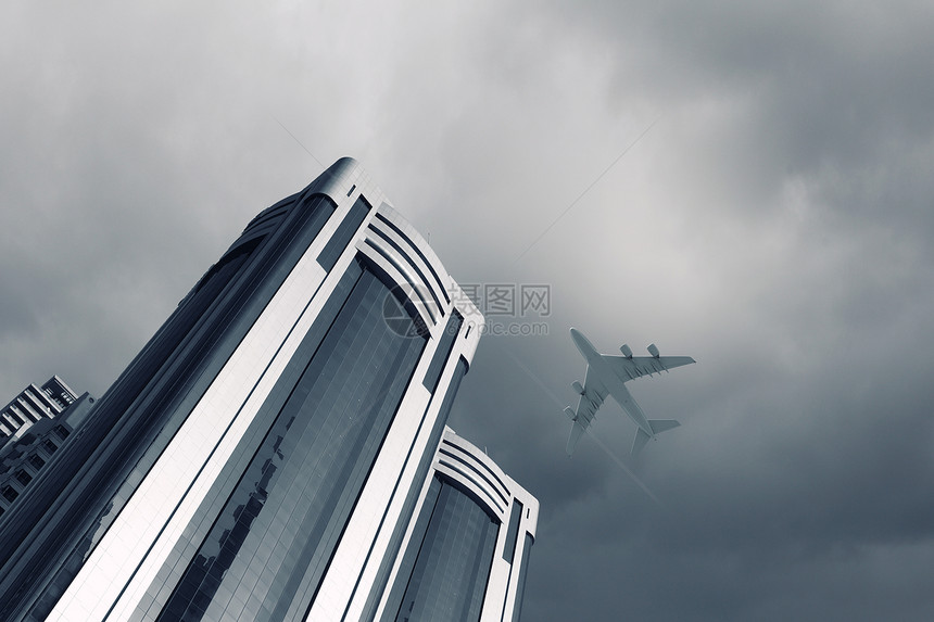 飞行飞机飞机摩天大楼上方飞行的底部视图图片