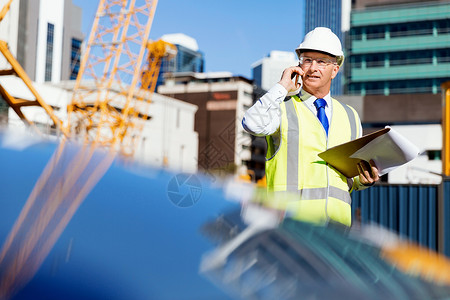 建筑工地的工程师建设者工程师建筑工人施工场景穿着安全背心记事本图片