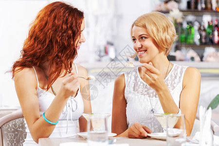 吃饭女孩咖啡馆里可爱的女孩两个轻漂亮的女人坐咖啡馆里吃甜点背景