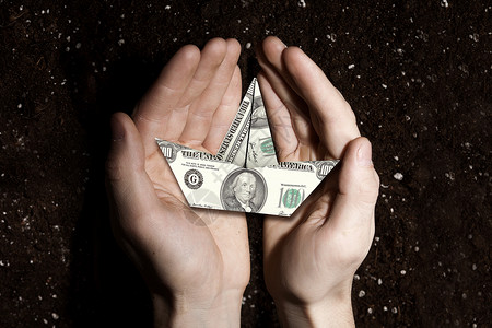 手握美元钞票船背景土壤丰富的土壤为你的收入图片