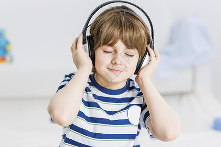 喜欢音乐男孩可爱的男孩戴着耳机,享受音乐喜欢这首歌背景