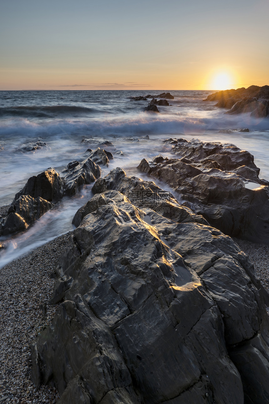 美丽的日落景观图像平静的海洋与岩石海岸线图片