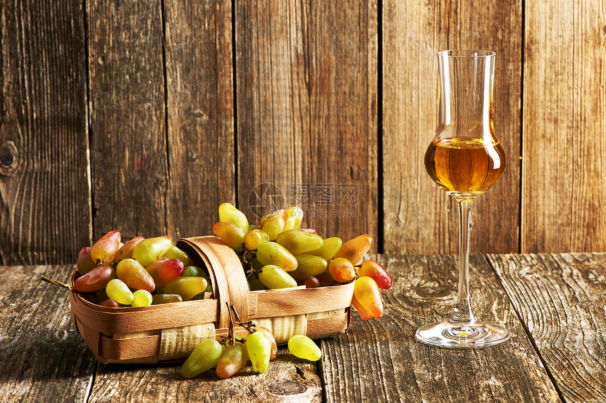 旧木桌上的新鲜葡萄杯格拉巴酒图片