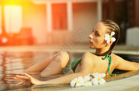 热带游泳池里的女孩,头发上花背景图片