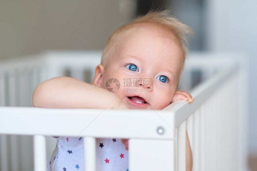 蓝眼睛的小男孩站婴儿床上图片