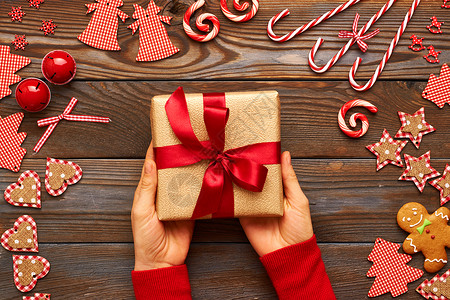 女人着木制背景的诞礼物,自制的姜饼饼干手工装饰图片