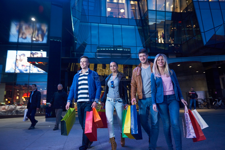 群朋友享受购物之旅xa群快乐的轻兄弟会享受购物之夜,并晚上与购物中心后台步行图片