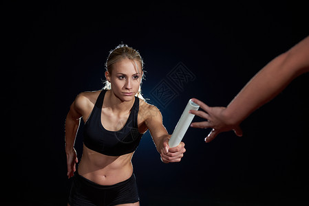 女子运动员接力赛中传递接力棒图片