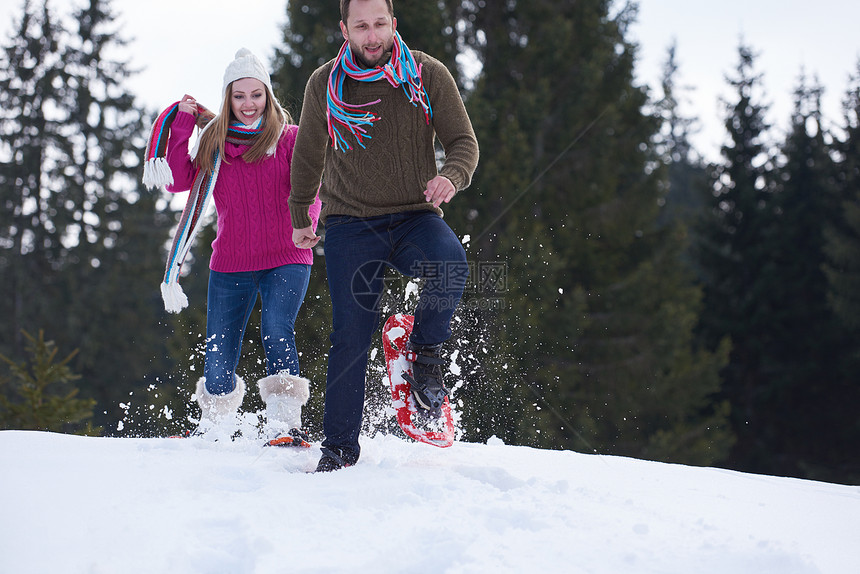 快乐的轻夫妇玩得开心,美丽的冬天穿着雪鞋户外散步健康运动放松图片