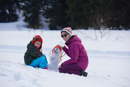 快乐的轻家庭新鲜的雪中玩耍,美丽的阳光明媚的冬天户外堆雪人图片