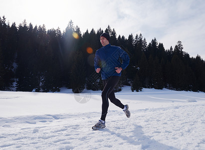 轻人森林里雪地上慢跑,阳光明媚的冬日英俊的运动阿特尔男人跑步图片