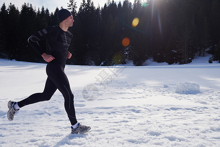 轻人森林里雪地上慢跑,阳光明媚的冬日英俊的运动阿特尔男人跑步图片