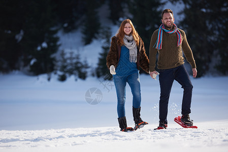 快乐的轻夫妇玩得开心,穿着雪鞋散步浪漫的冬季放松场景图片