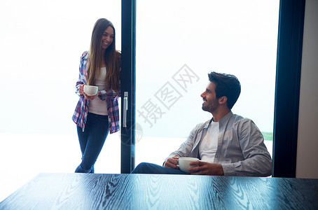 放松的轻夫妇喝天早上的咖啡,大明亮的窗户现代家庭别墅内部图片