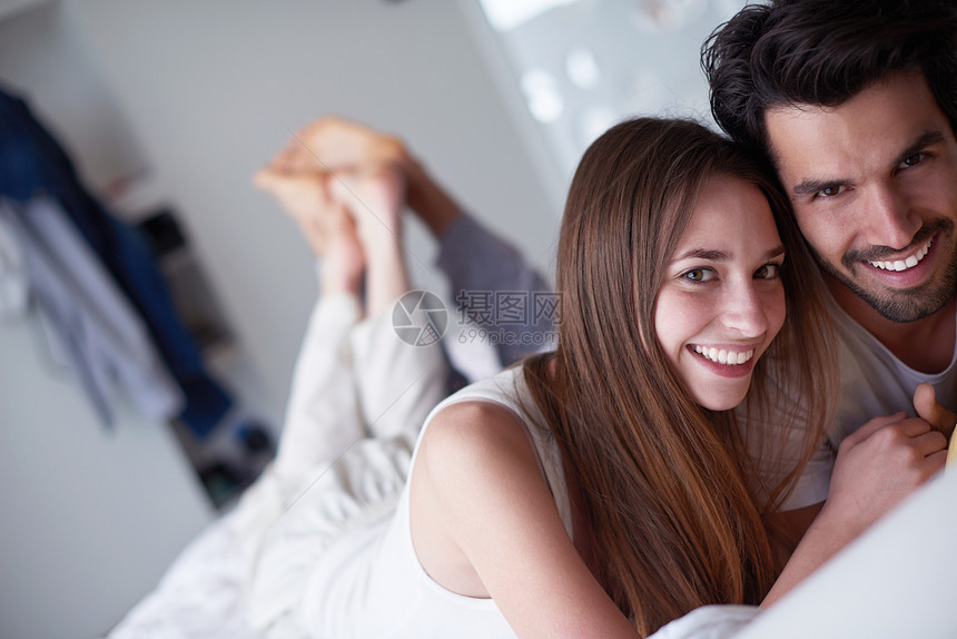 快乐的轻夫妇放松,床上玩得开心图片