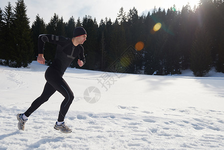 阿甘奔跑轻人森林里雪地上慢跑,阳光明媚的冬日英俊的运动阿特尔男人跑步背景