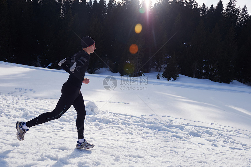 轻人森林里雪地上慢跑,阳光明媚的冬日英俊的运动阿特尔男人跑步图片