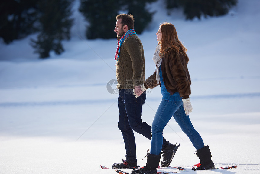 快乐的轻夫妇玩得开心,穿着雪鞋散步浪漫的冬季放松场景图片