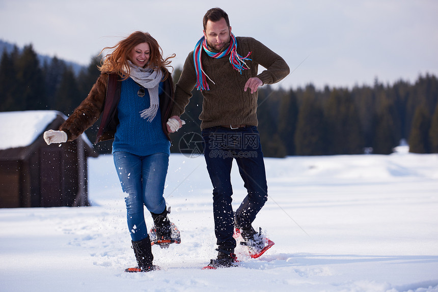 快乐的轻夫妇玩得开心,穿着雪鞋散步浪漫的冬季放松场景图片