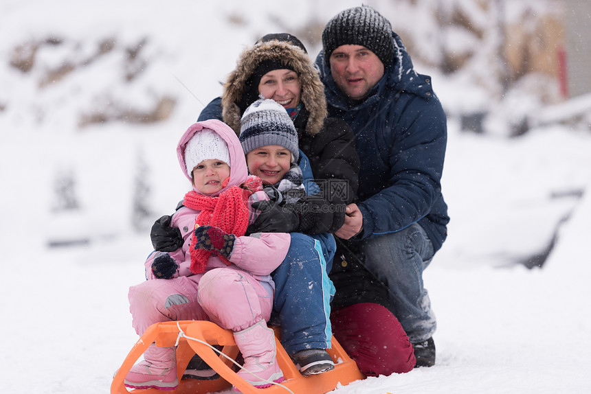 快乐的轻家庭肖像寒假,而坐雪橇风景与新鲜的落雪图片