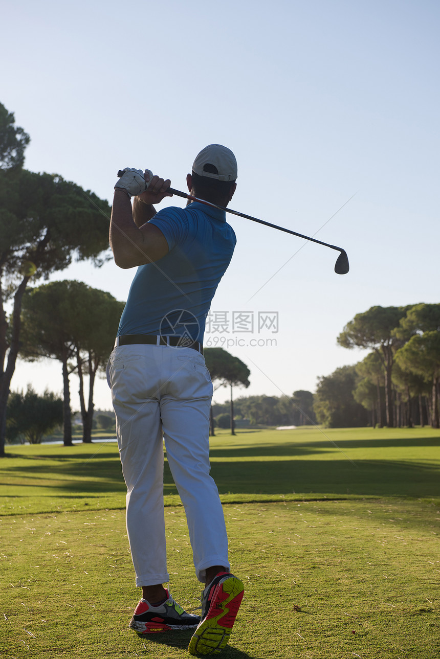 高尔夫球手击球与球杆美丽的早晨与太阳耀斑背景图片