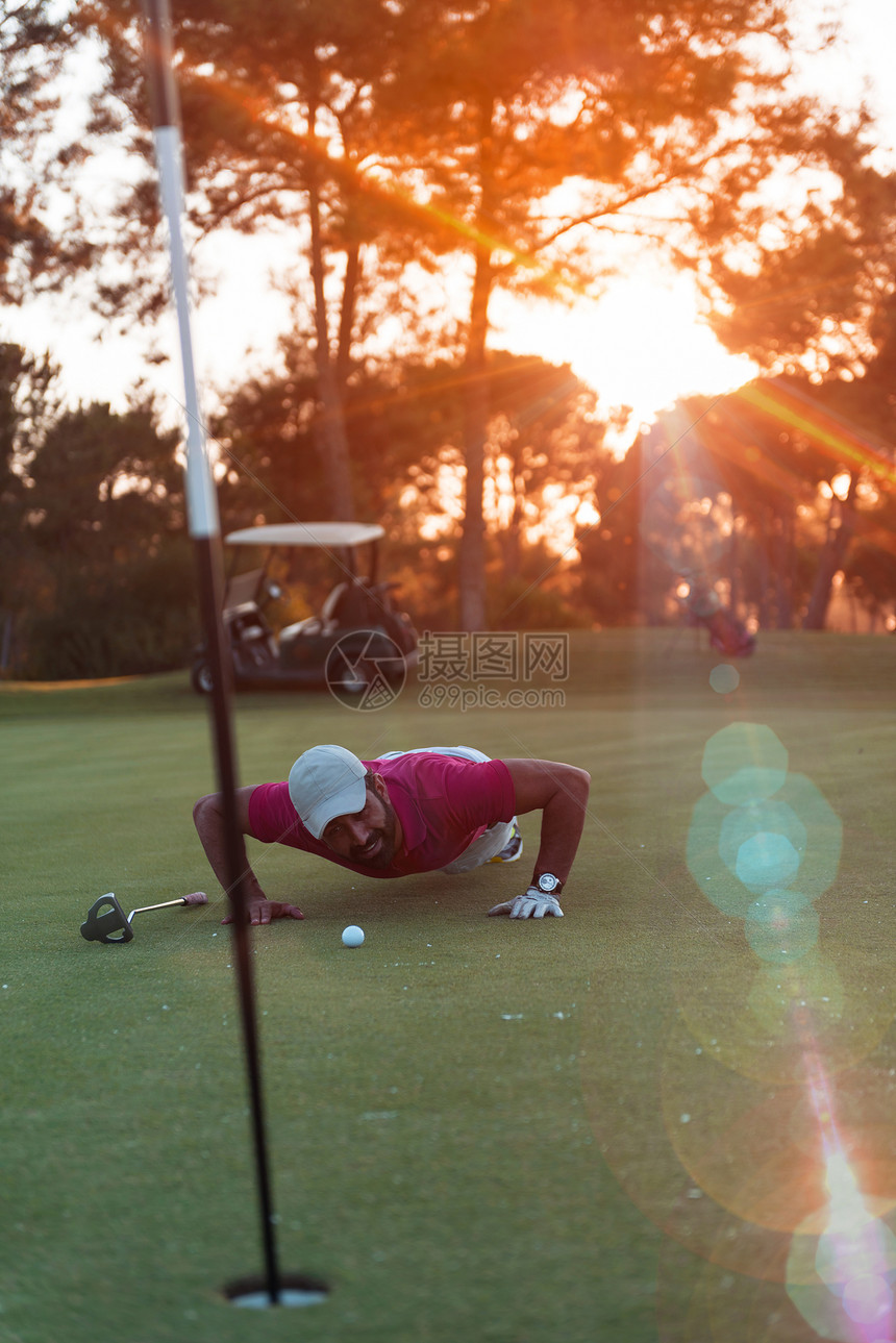高尔夫球运动员洞里球欺骗成功的,美丽的日落后台图片